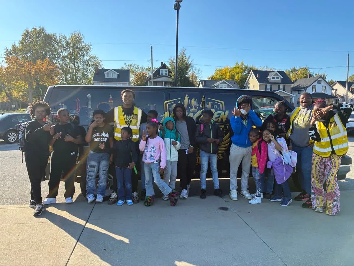 Children and New Gen team members together beside the black-and-gold New Gen Frontline 216 van