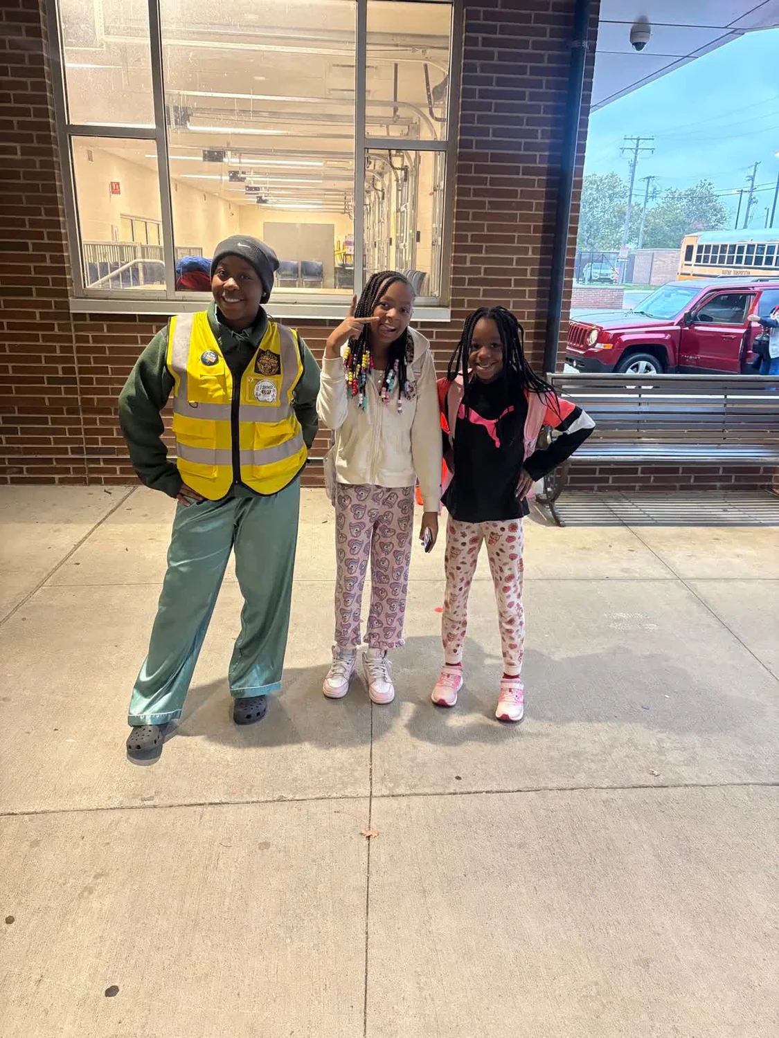 A New Gen team member in a yellow vest smiling with two children