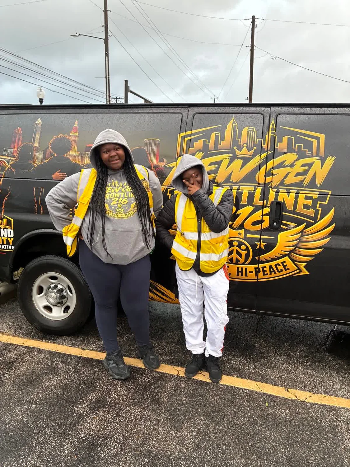 Two New Gen team members in branded clothing and yellow vests beside the van’s large New Gen Frontline 216 logo