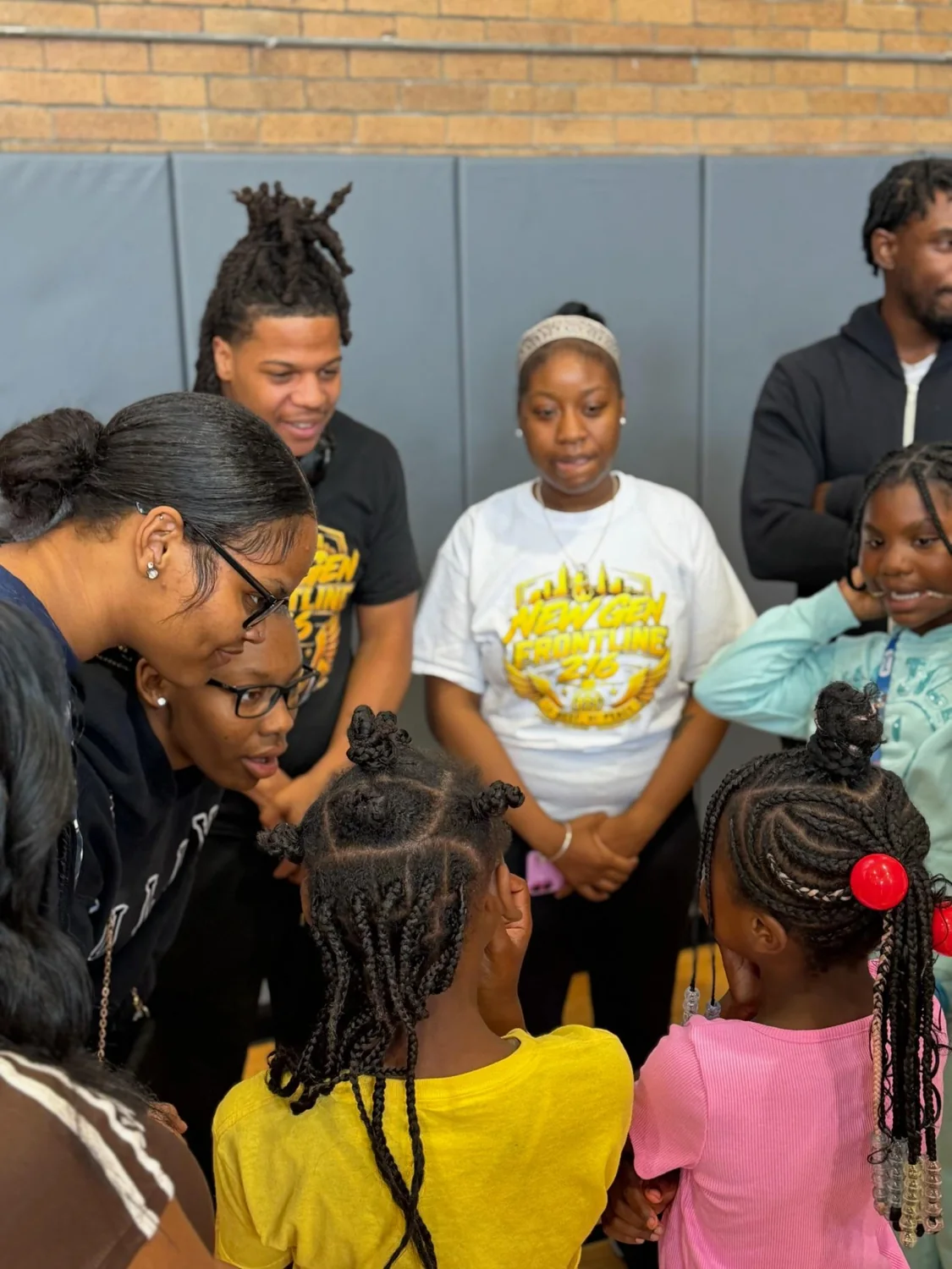 New Gen team members listening and talking with children in a gym