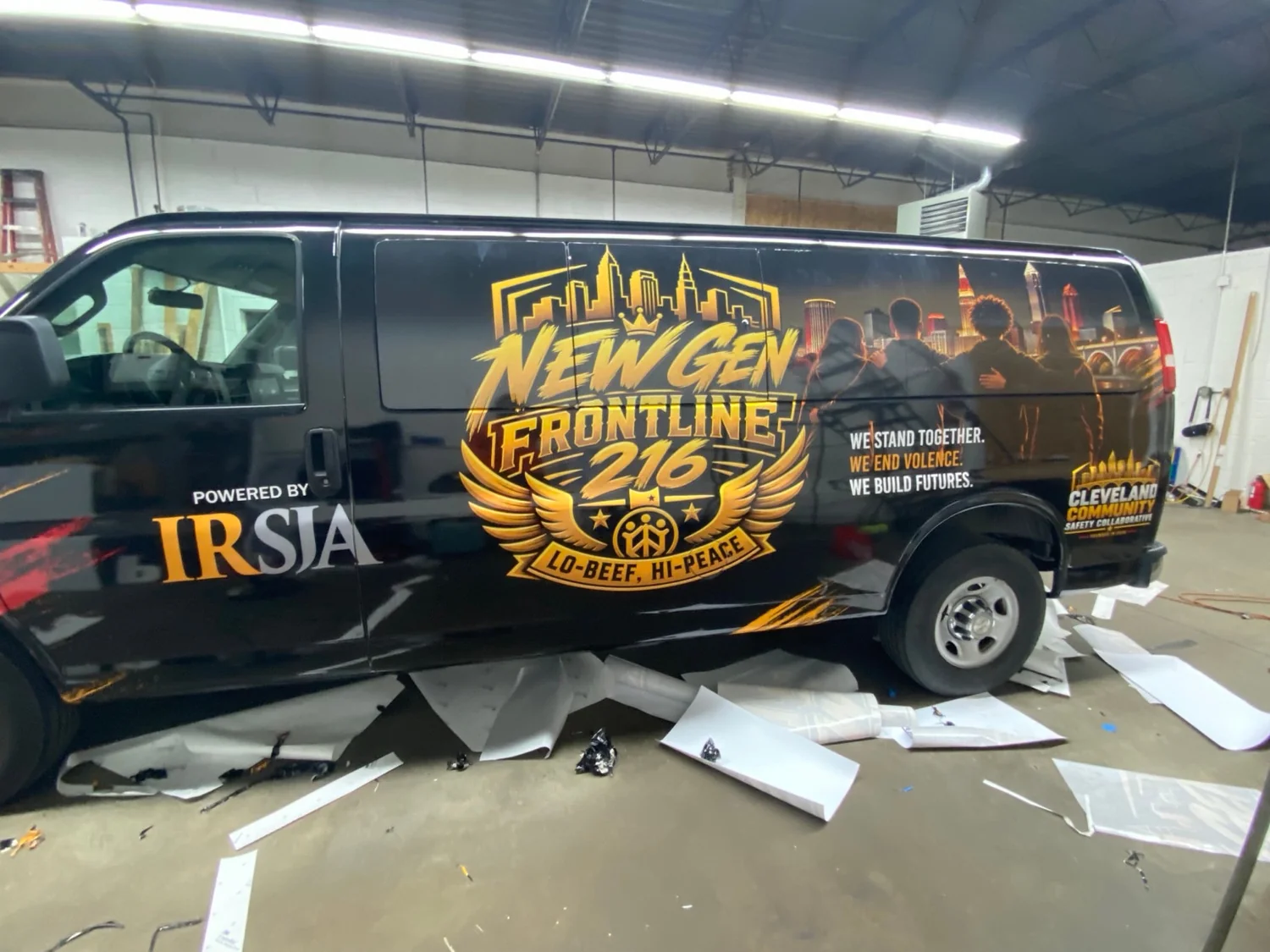 Side view of the actual New Gen Frontline 216 van showing its New Gen logo, IRSJA and Cleveland Community Safety Collaborative branding
